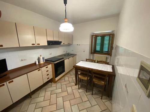 una cocina con armarios blancos y una mesa con sillas. en Lo Sdrucciolo, en Laterina