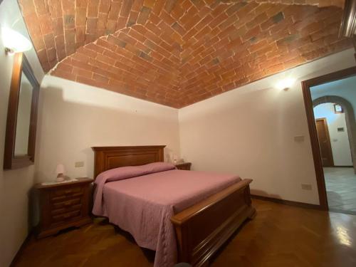 1 dormitorio con cama y pared de ladrillo en Lo Sdrucciolo, en Laterina