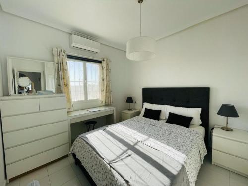 a white bedroom with a bed and a window at Casa Linda in Rojales