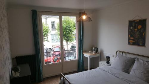 1 dormitorio con 1 cama y ventana con balcón en Chambres d'hôtes au centre de Guémené-sur-Scorff en Guéméné-sur-Scorff