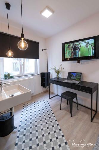 a living room with a desk and a tv on the wall at Sali Homes - GaesteHaus Lamm Obersulm in Obersulm