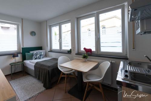 a bedroom with a bed and a table and windows at Sali Homes - GaesteHaus Lamm Obersulm in Obersulm