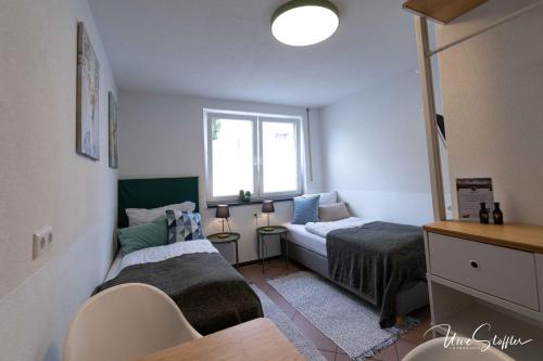 a small bedroom with two beds and a window at Sali Homes - GaesteHaus Lamm Obersulm in Obersulm