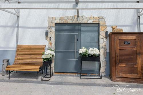 a wooden bench and a door with flowers on it at Sali Homes - GaesteHaus Lamm Obersulm in Obersulm