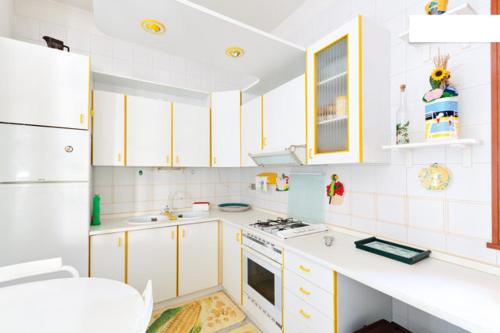 een keuken met witte apparaten en gele kasten bij Villetta a 10 minuti, a piedi, dalla spiaggia in San Vito lo Capo
