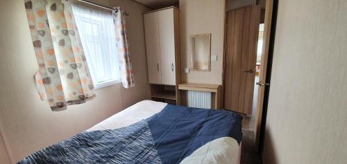 Habitación pequeña con cama y ventana en Remarkable 5-Bed Cabin in Clacton-on-Sea, en Clacton-on-Sea