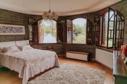 a bedroom with a bed and some windows at Casa de Pedra na Serra Gaucha in Carlos Barbosa