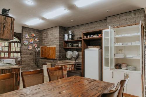 a kitchen with a wooden table and a white refrigerator at Casa de Pedra na Serra Gaucha in Carlos Barbosa