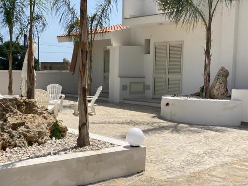 eine Terrasse mit Stühlen und Palmen vor einem Haus in der Unterkunft Case Vacanze Giovanna in Petrosino
