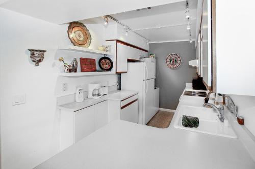 a white kitchen with two sinks and a refrigerator at Condo Casa Verde in Palm Springs