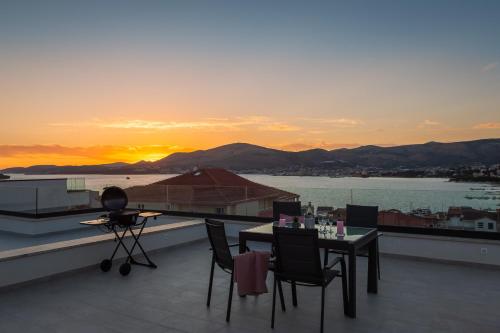 a balcony with a table and chairs and a sunset at Luxury Apartment Dreams in Okrug with swimming pool, sea view, Wifi, parking in Trogir
