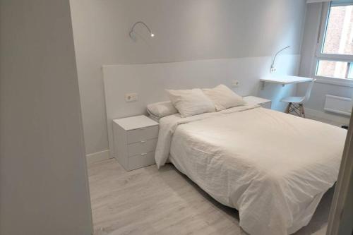 a white bedroom with a bed and a window at Apartamento recién reformado en Barakaldo in Barakaldo