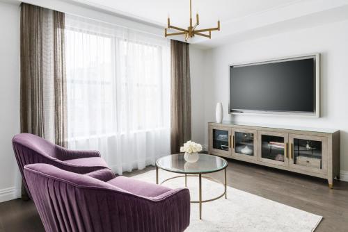 a living room with a tv and two chairs and a table at The Wallace Hotel in New York