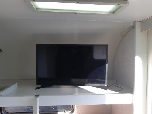 einen Flachbild-TV auf einem weißen Regal in der Unterkunft Trailer novo completo. in Bagé