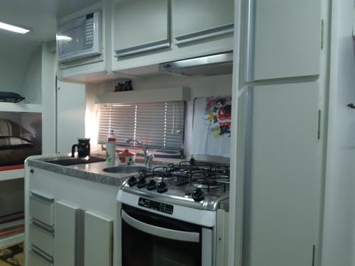 a kitchen with a stove and a sink at Trailer novo completo. in Bagé