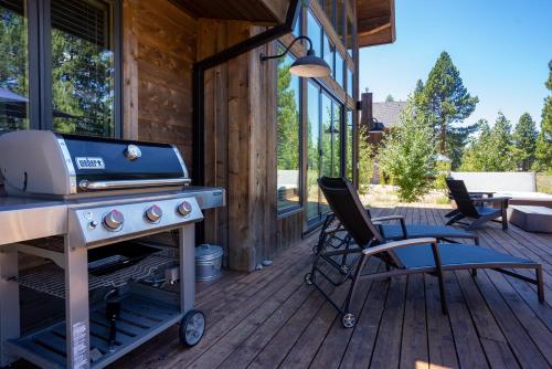 a grill on a deck with a chair and a table at NEW 4BD Residence in the Signature Home Collection at Old Greenwood! in Truckee