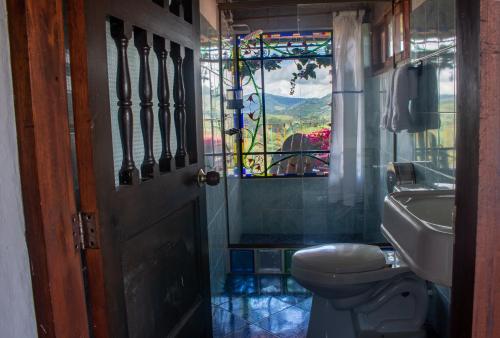 a bathroom with a toilet and a stained glass window at Hotel Villa Palosanto in Jericó
