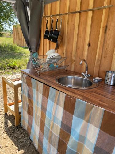 um balcão de cozinha com um lavatório numa parede de madeira em Terra-Tipike, Tipi à la ferme entre Terre et Mer em Trébry