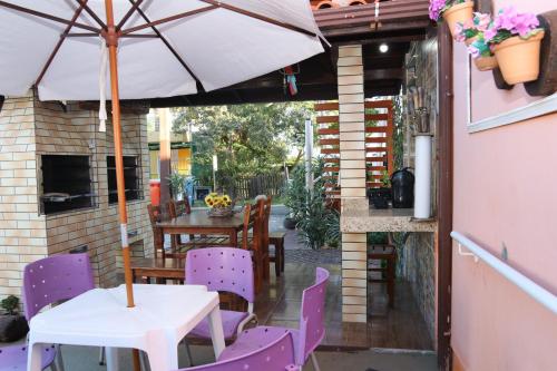 une terrasse avec des chaises violettes et une table avec un parasol dans l'établissement Residencial Maria Antonia, à Florianópolis