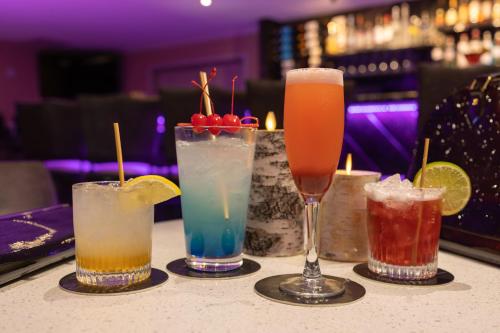 four cocktails sitting on a table in a bar at Wyndham Garden Galena Hotel & Day Spa in Galena
