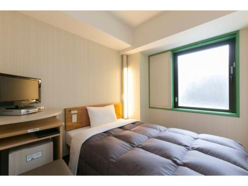 a hotel room with a bed and a television at R&B Hotel Kanazawa Station Nishiguchi - Vacation STAY 39074v in Kanazawa