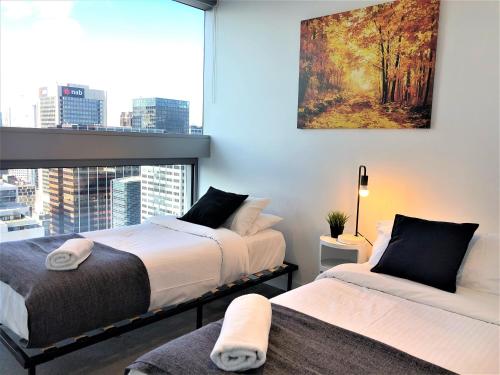 a bedroom with two beds and a large window at ReadySet Apartments on Rose Lane in Melbourne