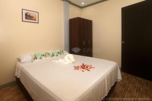a bedroom with a bed with white sheets and flowers on it at AJ Residences Apartelle in San Francisco