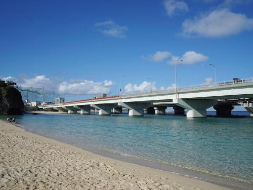 a bridge over the water with a sandy beach at HOTEL SANSUI NAHA Ryukyu Onsen Naminoue-No-Yu in Naha