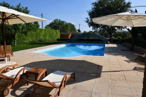 une piscine avec des chaises et un parasol dans l'établissement La Maison Angelvin, à Puimoisson