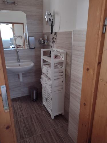 a bathroom with a sink and a white shelf with towels at Bara ház in Tvrdošovce