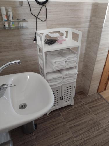 a bathroom with a sink and a shelf with towels at Bara ház in Tvrdošovce