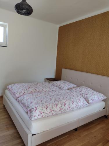 een slaapkamer met een wit bed met bloemen erop bij Bara ház in Tvrdošovce
