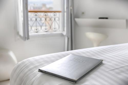 a notebook sitting on top of a white bed at Blc Design Hotel in Paris