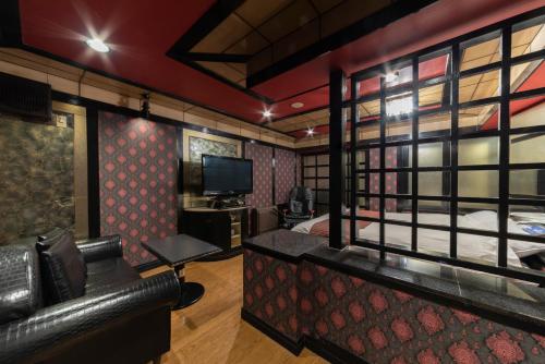 a room with a bed and a couch and a tv at Hotel Chapel Story Sakai in Sakai