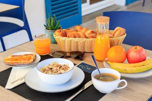 einen Tisch mit Teller mit Lebensmitteln und einem Obstkorb in der Unterkunft Hôtel Flor in Saint-Florent