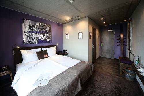 Altes Stahlwerk Business & Lifestyle Hotel في نويمونستر: غرفة نوم بسرير كبير في غرفة