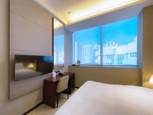 a hotel room with a bed and a desk and a window at Louis Kienne Serviced Residences - Havelock in Singapore