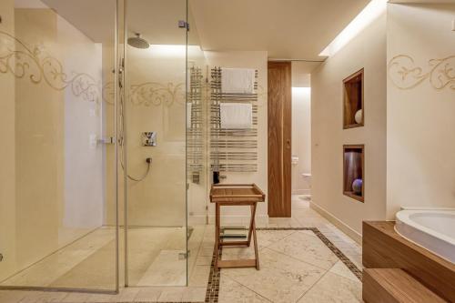 a bathroom with a glass shower and a stool at Wald & Schlosshotel Friedrichsruhe in Friedrichsruhe