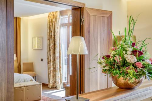 a hotel room with a vase of flowers on a table at Wald & Schlosshotel Friedrichsruhe in Friedrichsruhe