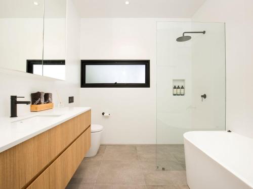 a bathroom with a tub and a toilet and a sink at Banksia I Absolute Beachfront in Culburra Beach