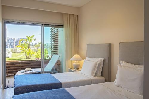 a hotel room with two beds and a window at Praia do Sal Resort in Alcochete