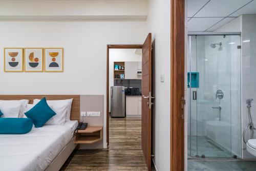 um quarto com uma cama e uma cabina de duche em vidro em SKYLA Serviced Apartments & Suites, Hi-Tech City em Hyderabad