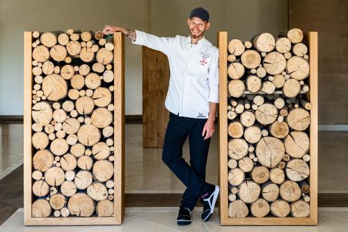 a man standing next to a pile of wood at Wald & Schlosshotel Friedrichsruhe in Friedrichsruhe