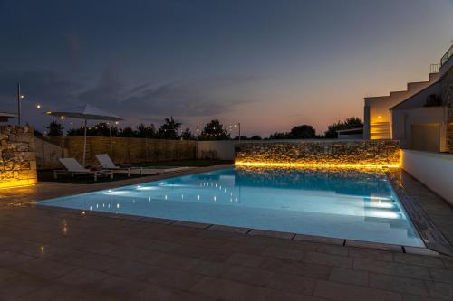 a swimming pool with lights in a backyard at night at Dimora Le Site in Torre Suda