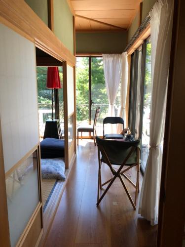 a living room with a chair and a table and windows at STAY FUJI a in Yamanakako