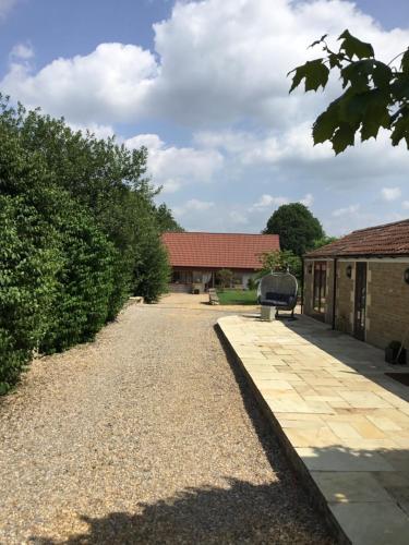 a gravel path leading to a building with a bench at Highcroft House in Corsham
