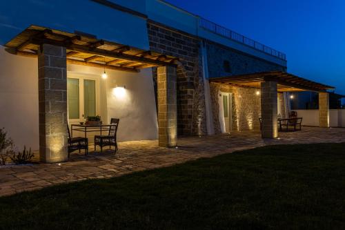 a patio with a table under a pergola at night at Dimora Le Site in Torre Suda