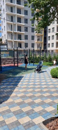 a woman walking with a baby stroller on a sidewalk at АПАРТАМЕНТЫ ВОЗЛЕ МОРЯ (КРАСИВЫЙ ЗАКАТ). in Odesa