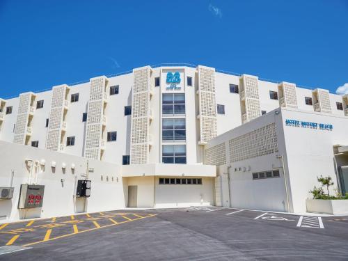 a large white building with a parking lot in front at Hotel Miyuki Beach in Onna