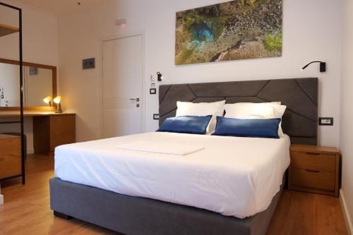 a bedroom with a large white bed with blue pillows at Hilltop Heaven Hotel in Sarandë